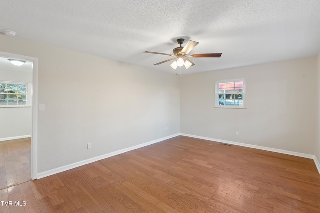 empty room with a textured ceiling, ceiling fan, and wood-type flooring