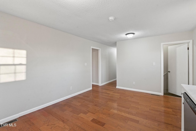 unfurnished room with wood-type flooring and a textured ceiling