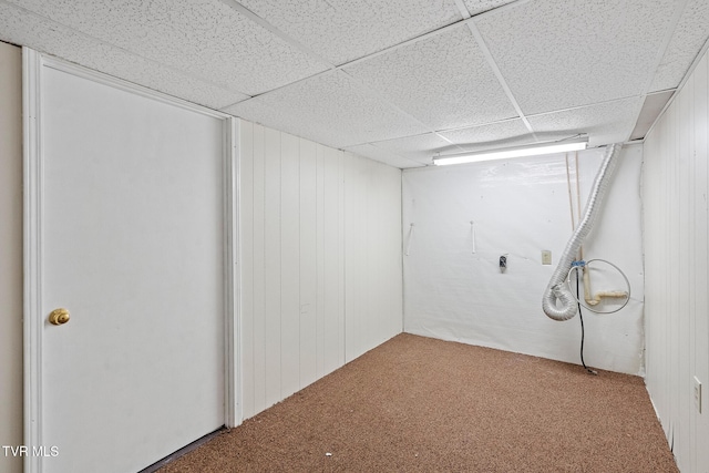 basement featuring a drop ceiling, wooden walls, and carpet floors