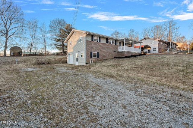 view of side of home with covered porch, a yard, and a garage