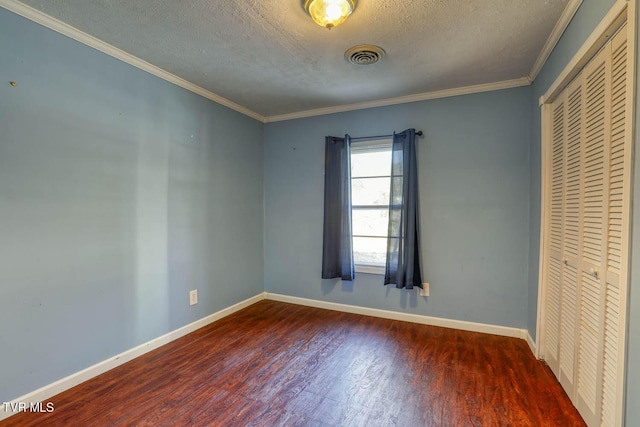 unfurnished bedroom with a textured ceiling, dark hardwood / wood-style floors, a closet, and ornamental molding