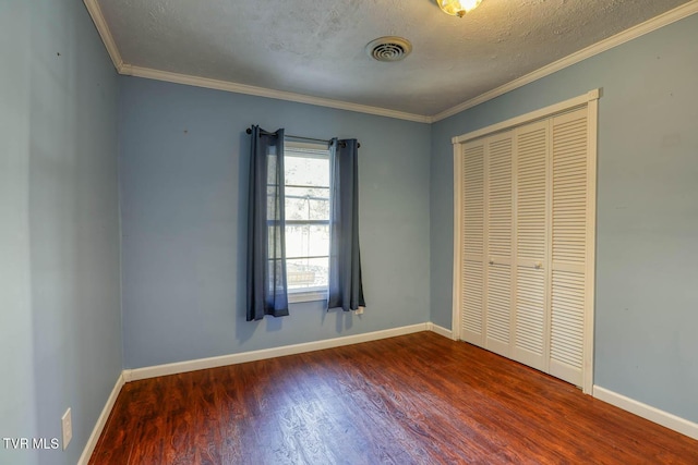 unfurnished bedroom featuring a closet, hardwood / wood-style flooring, ornamental molding, and a textured ceiling