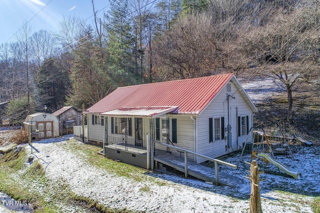 view of front of home with central air condition unit, a porch, and a shed