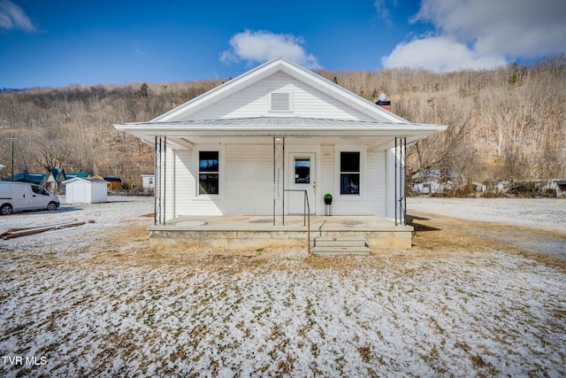 view of front of house featuring covered porch and a storage shed