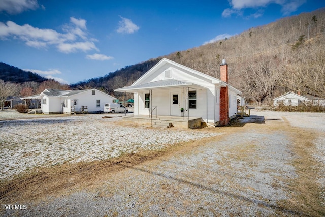 rear view of property featuring a mountain view and covered porch