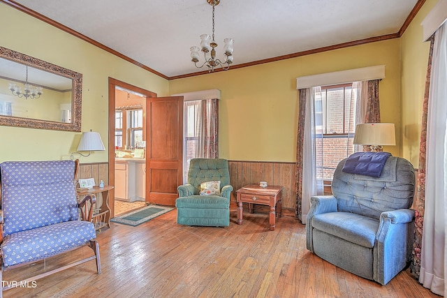 sitting room featuring light wood-type flooring, a chandelier, and ornamental molding