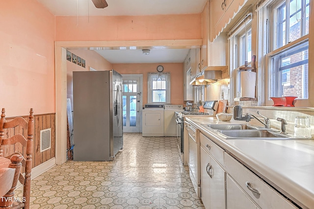 kitchen with white cabinets, washer and clothes dryer, dishwasher, stainless steel refrigerator with ice dispenser, and sink