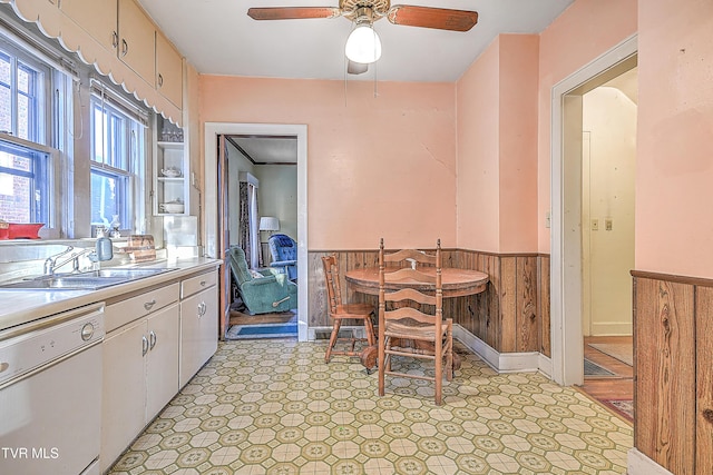 dining space with ceiling fan, sink, and wooden walls