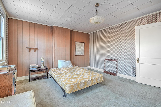 bedroom with wood walls, light colored carpet, and crown molding