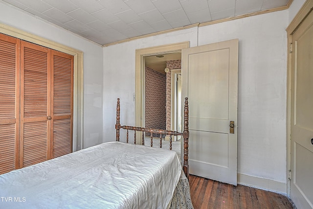 bedroom with a closet, ornamental molding, and dark hardwood / wood-style flooring