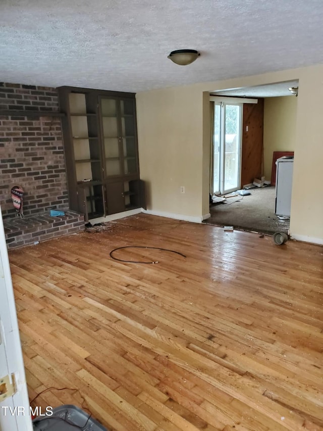 unfurnished living room with a textured ceiling and light hardwood / wood-style floors