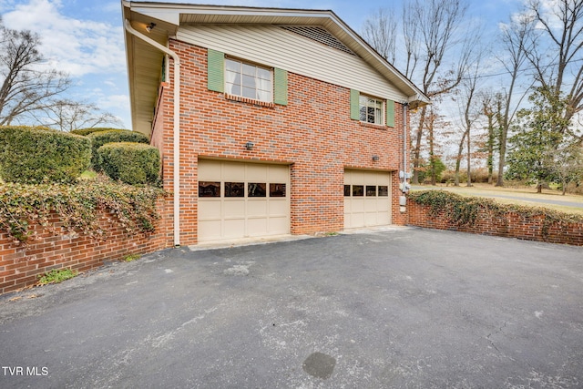 view of home's exterior featuring brick siding, driveway, and a garage