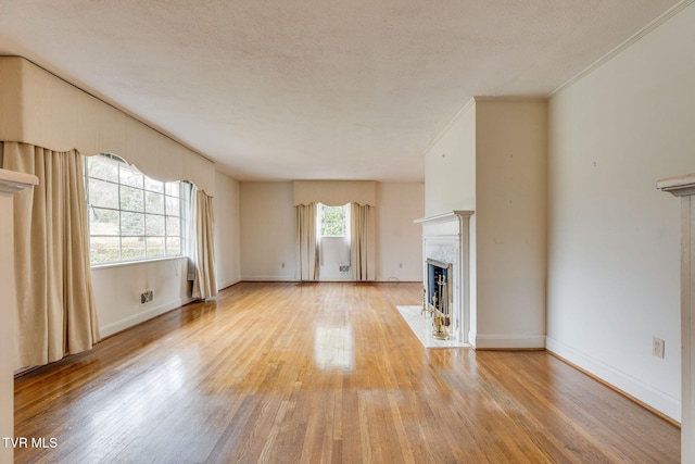 unfurnished living room with a fireplace, baseboards, light wood finished floors, and a textured ceiling