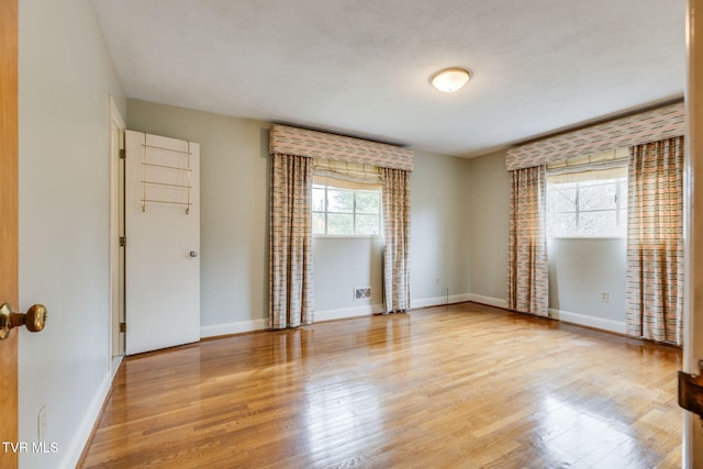 unfurnished room with a textured ceiling, baseboards, and wood finished floors