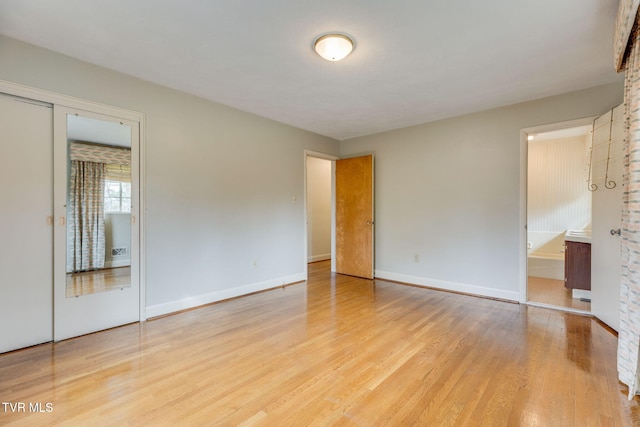 unfurnished bedroom with baseboards, light wood-type flooring, and connected bathroom