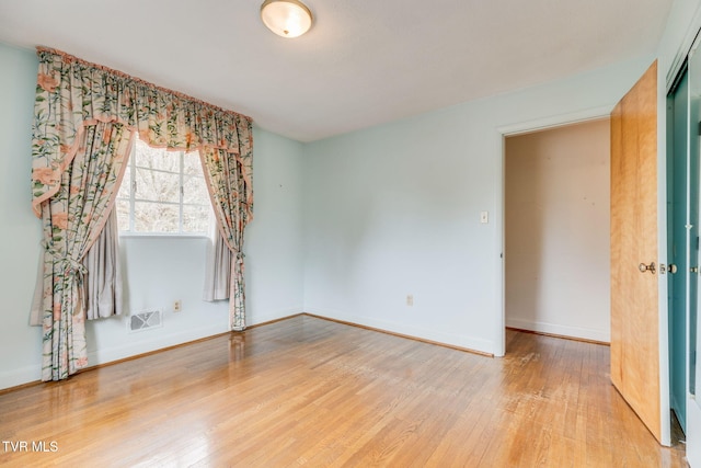 empty room with visible vents, baseboards, and wood finished floors