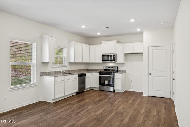 kitchen with sink, white cabinetry, appliances with stainless steel finishes, plenty of natural light, and dark hardwood / wood-style flooring