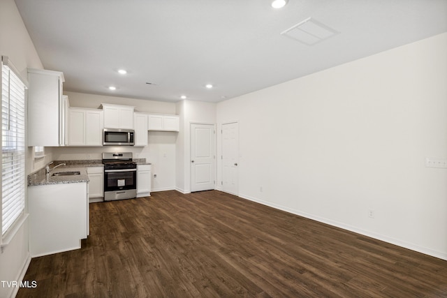 kitchen with sink, white cabinetry, stainless steel appliances, dark hardwood / wood-style flooring, and light stone counters