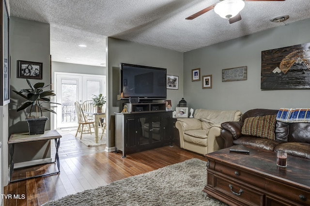 living room with ceiling fan, hardwood / wood-style floors, and a textured ceiling