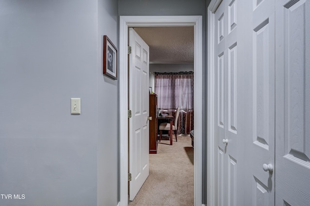 hall with light carpet and a textured ceiling