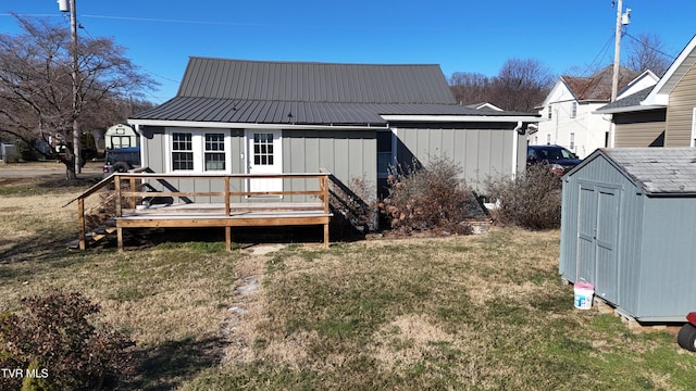 back of house featuring a deck, a lawn, and a storage shed