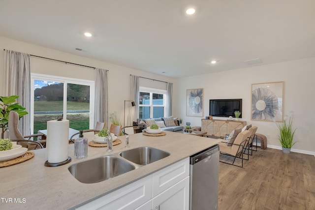 kitchen with light wood-style flooring, a sink, stainless steel dishwasher, white cabinetry, and recessed lighting