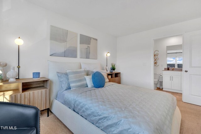 bedroom featuring light carpet, radiator, and ensuite bath