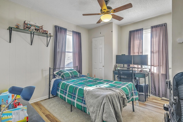 bedroom featuring ceiling fan, wood-type flooring, and a textured ceiling