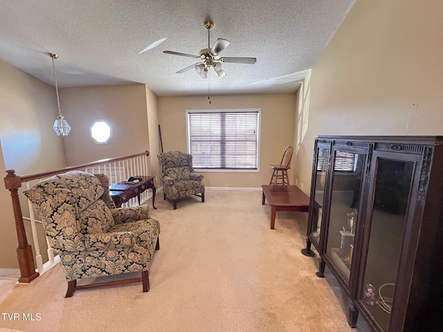 sitting room featuring ceiling fan, light colored carpet, and a textured ceiling