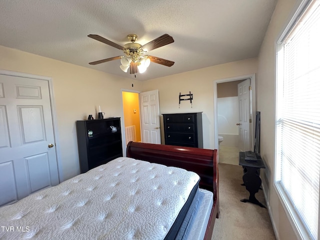 carpeted bedroom with ceiling fan, multiple windows, connected bathroom, and a textured ceiling