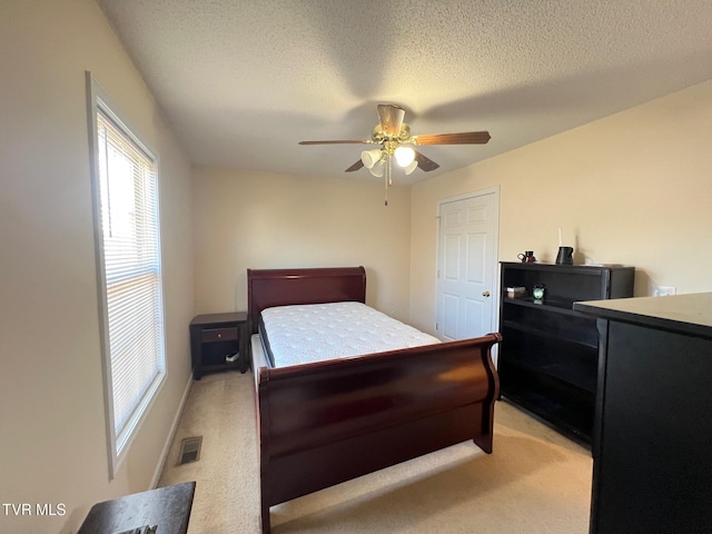 carpeted bedroom with ceiling fan and a textured ceiling