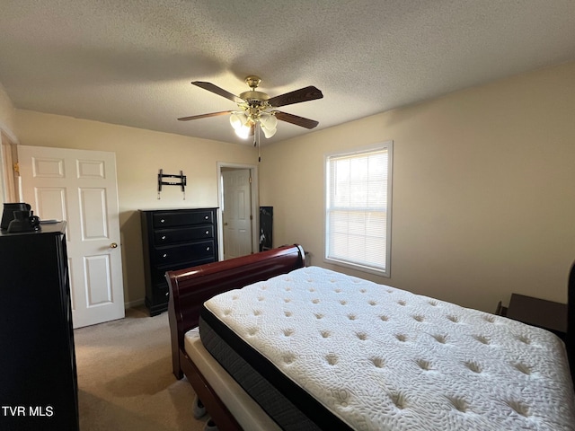 bedroom featuring light carpet, ceiling fan, and a textured ceiling