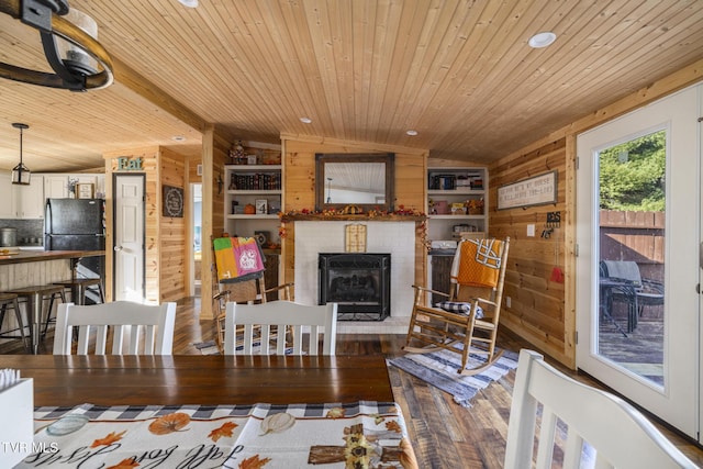 dining space featuring lofted ceiling with beams, hardwood / wood-style floors, and wood walls