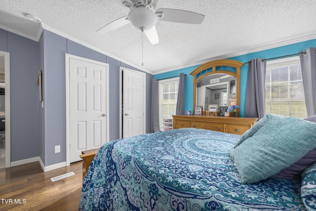 bedroom with dark hardwood / wood-style flooring, crown molding, multiple windows, and a textured ceiling