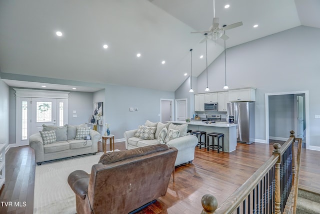 living room with high vaulted ceiling, ceiling fan, and light wood-type flooring