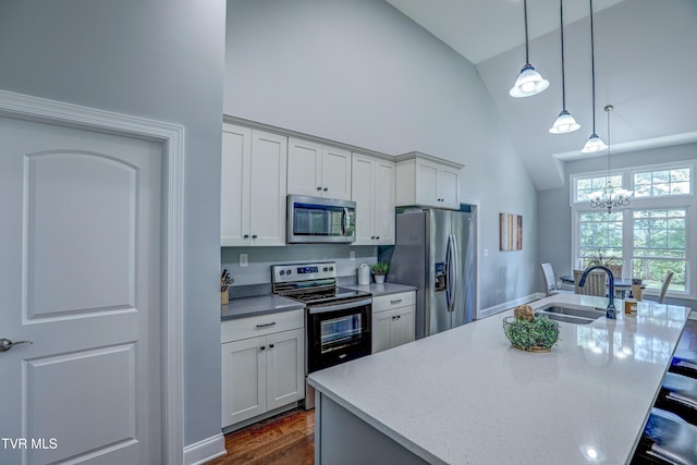 kitchen with stainless steel appliances, sink, hanging light fixtures, light stone counters, and a center island with sink