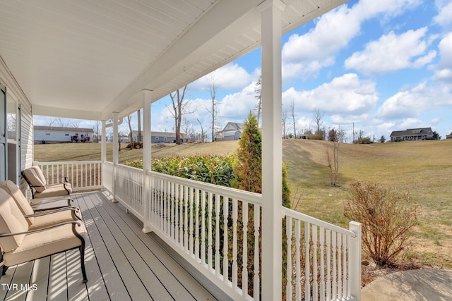 wooden deck featuring a porch, a yard, and a rural view