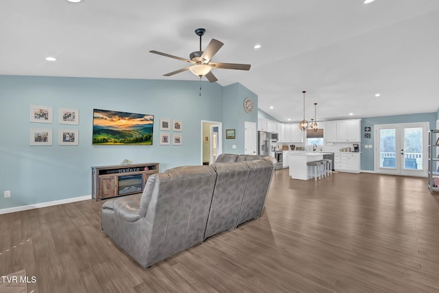 living room with vaulted ceiling, dark hardwood / wood-style floors, ceiling fan with notable chandelier, and french doors