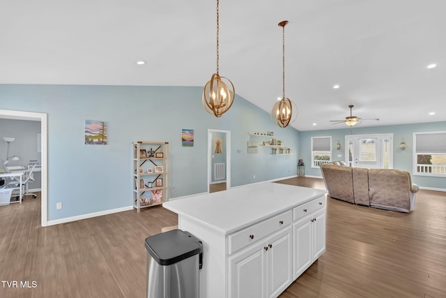 kitchen with lofted ceiling, white cabinetry, a center island, hanging light fixtures, and light hardwood / wood-style flooring