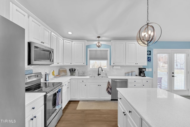 kitchen featuring white cabinetry, stainless steel appliances, sink, and pendant lighting