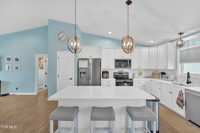 kitchen featuring white cabinetry, stainless steel appliances, sink, and vaulted ceiling