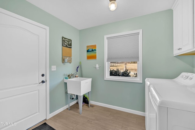 washroom featuring light hardwood / wood-style floors, washing machine and dryer, and cabinets