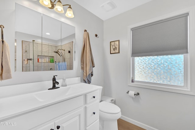 bathroom featuring vanity, wood-type flooring, toilet, and tiled shower