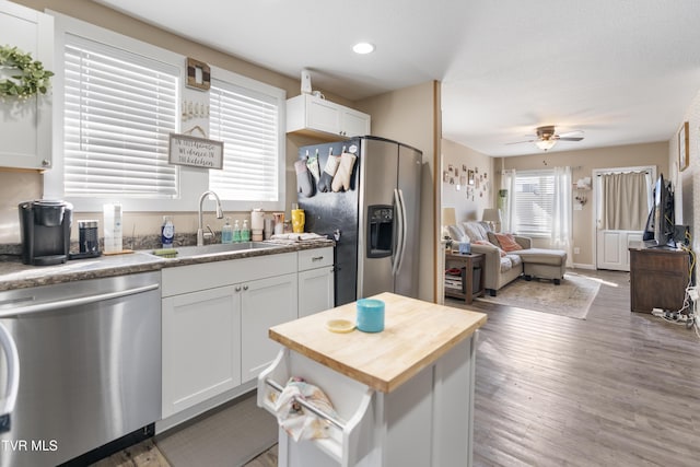 kitchen featuring stainless steel appliances, a kitchen island, sink, and white cabinets