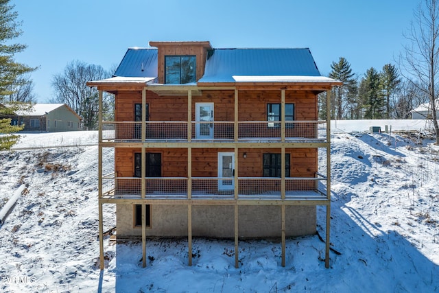 snow covered back of property featuring a balcony