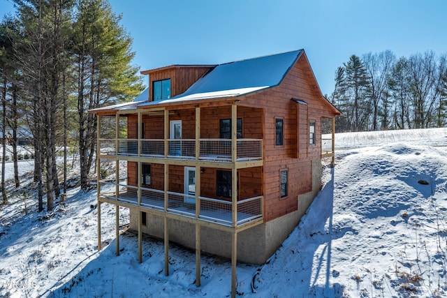 snow covered rear of property featuring a balcony