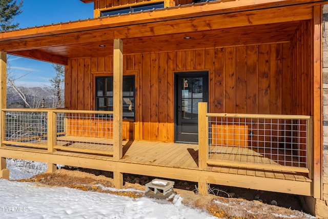 snow covered deck featuring a porch