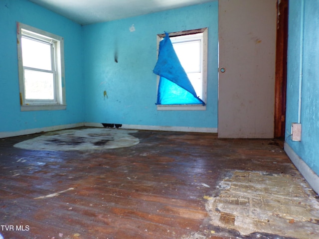 empty room featuring plenty of natural light and dark wood-type flooring