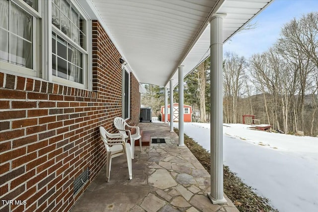 snow covered patio featuring a shed and central air condition unit