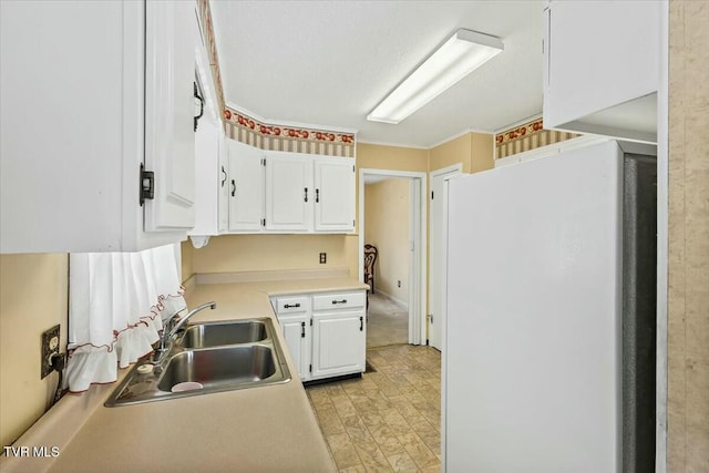 kitchen with white cabinetry, white fridge, and sink